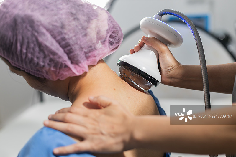 特写展示冲击波治疗探头在患者颈部和肩部进行治疗，用于慢性疼痛缓解和康复概念。图片素材