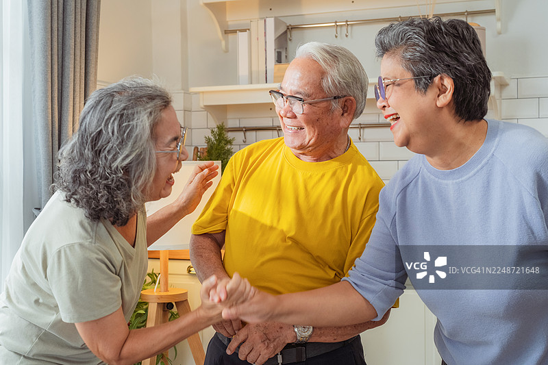 一群亚洲退休老友在充满美好氛围和快乐的背景下，在家中欢笑、微笑、交谈，享受新鲜的情感交流和快乐的友谊，共度周末时光。图片素材