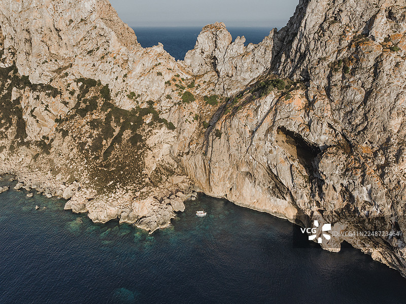 无人机航拍画面，显示一艘船在西班牙巴利阿里群岛伊维萨岛埃斯维德拉岛旁避风图片素材
