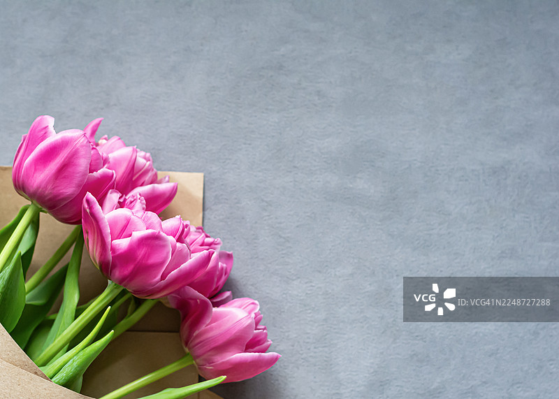 灰色背景上的新鲜郁金香。居家室内。母亲节或生日的祝贺花束。图片素材