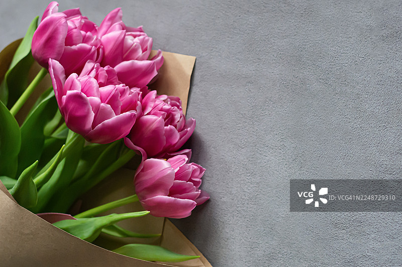 灰色背景上的新鲜郁金香。家居室内。母亲节或生日的祝贺花束。图片素材