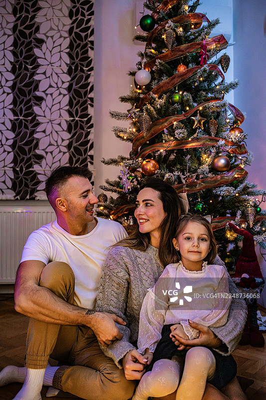 圣诞晚上一家人在圣诞树前温馨相聚。包括节礼日、假日季以及新年庆祝活动。图片素材