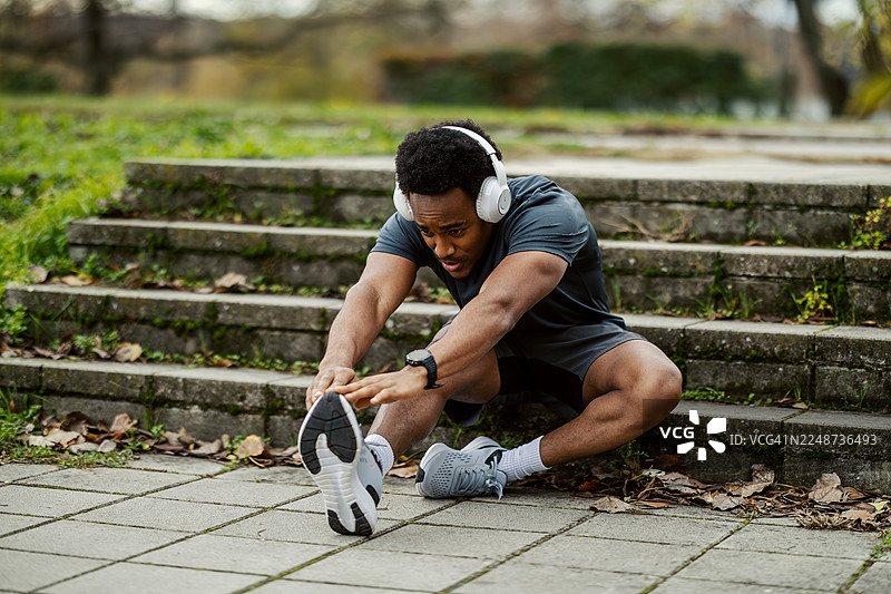 年轻男子在公园锻炼前伸展腿部图片素材