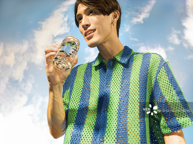 身穿条纹衬衫的年轻男子饮用饮料，背景有微芯片图片素材