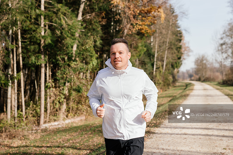 一名男性跑者在自然小径上朝镜头方向慢跑图片素材