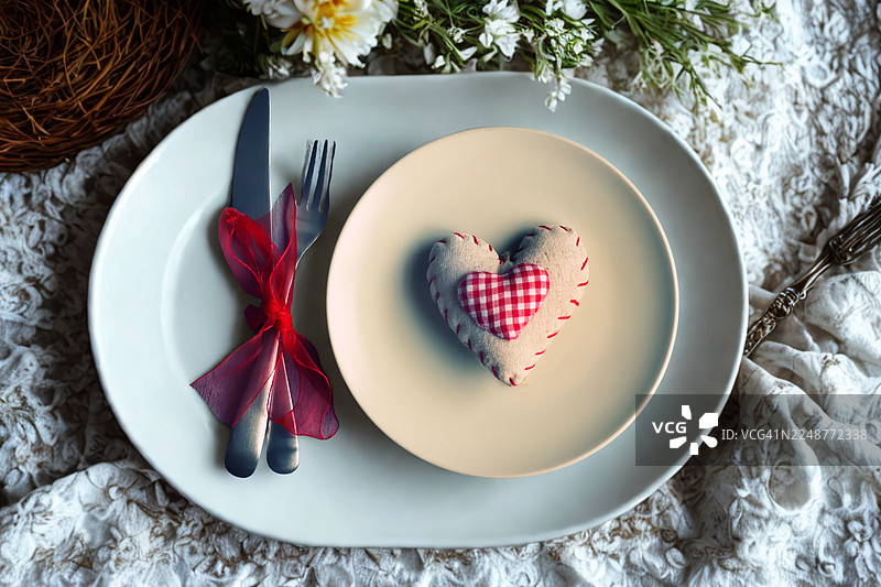 俯视餐桌上心形餐盘里的鲜花，准备一顿浪漫大餐图片素材