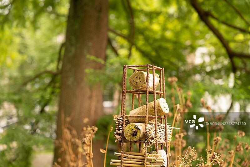 特写镜头：一个装饰精美的昆虫酒店，由木头和竹子构成，置身于葱郁的绿色花园中图片素材