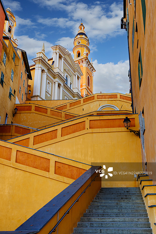 法国蔚蓝海岸芒通，一座历史悠久的教堂和色彩缤纷的建筑，搭配蜿蜒的楼梯，低角度视角图片素材