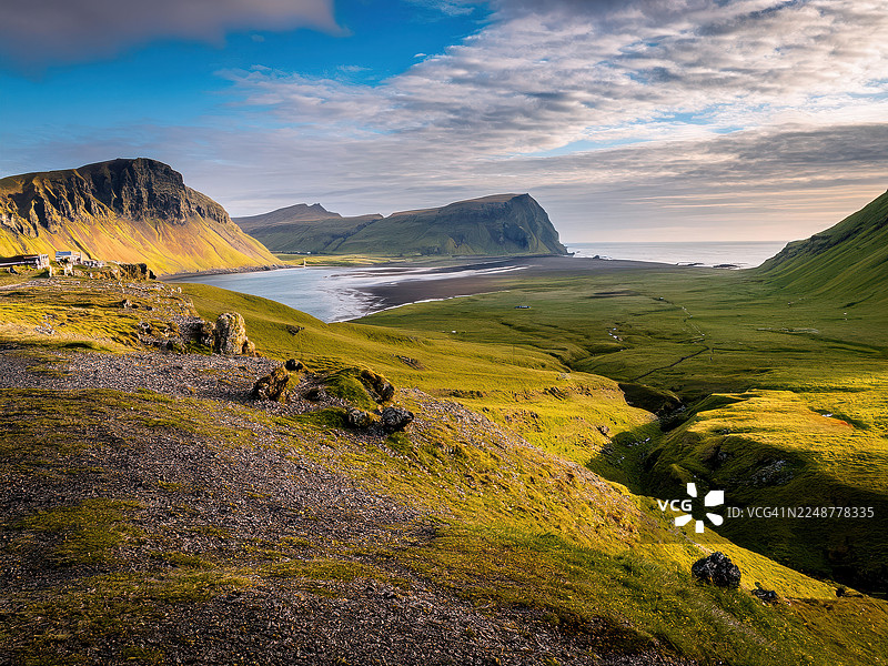 冰岛霍恩斯特兰迪尔自然保护区，动态天空下，绿色山谷通往大海的壮丽景色图片素材