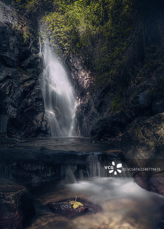 阿尔及利亚斯基克达，郁郁葱葱的岩石森林景观中宁静的瀑布飞流直下，水流平缓图片素材