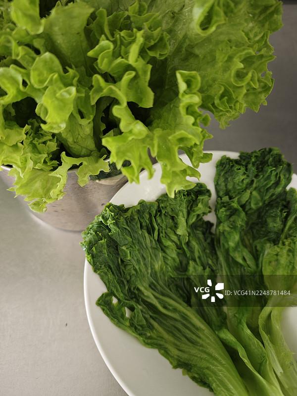 新鲜的绿色生菜叶装在碗里和盘子里，准备好享用健康的餐点图片素材