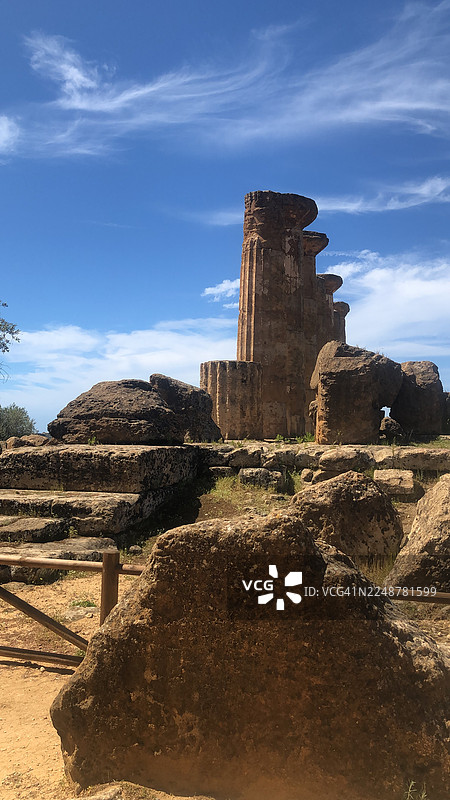 从低角度仰望古老的遗迹，背景是蔚蓝的天空和缕缕白云，散发着历史的厚重感与宏伟气势，意大利阿格里真托，神殿之谷图片素材