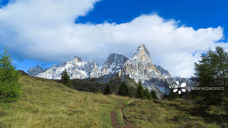 意大利普里梅罗圣马蒂诺迪卡斯特罗扎，蓝天白云下，雪山环绕的绿色山丘与蜿蜒小径的全景图片素材