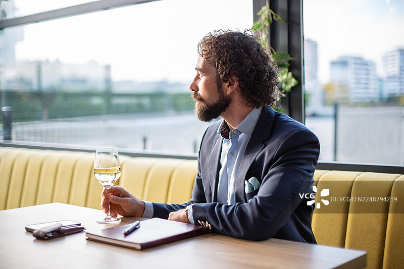 一位沉思的商人正在餐厅里喝白葡萄酒图片素材