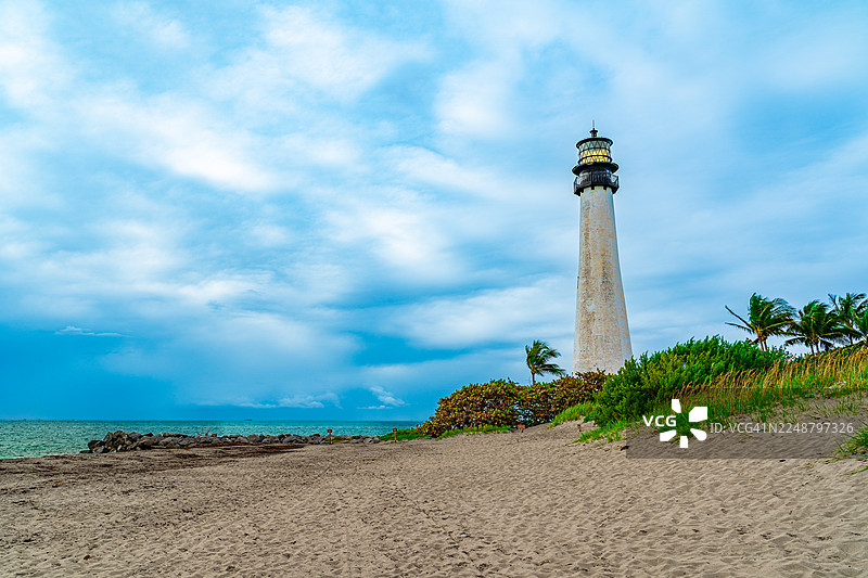 美国基斯凯恩岛历史悠久的灯塔，背景是沙滩和多云的天空图片素材