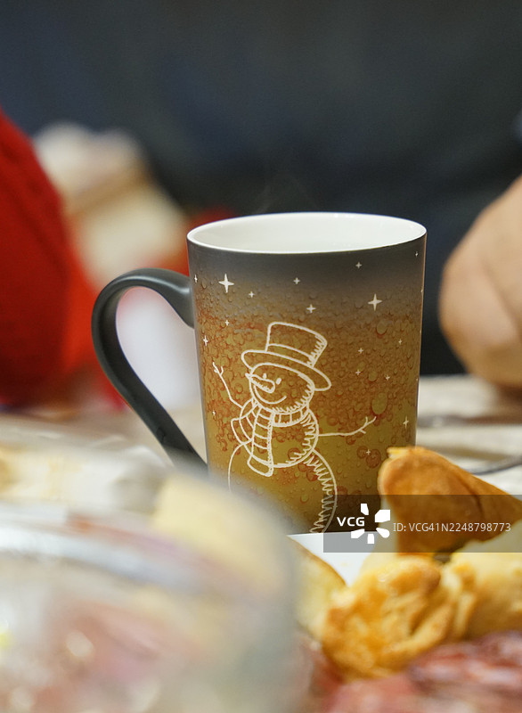 桌上用节日雪人马克杯盛放的热饮，营造出温馨的冬日氛围图片素材