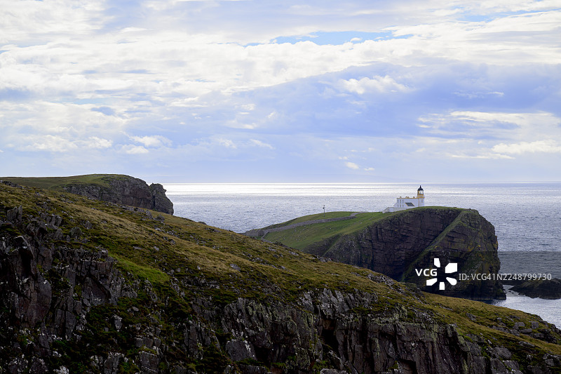 苏格兰斯托尔灯塔，位于罗金弗附近崎岖的悬崖上，俯瞰着广阔、波光粼粼的大海，天空多云，风景戏剧化。图片素材