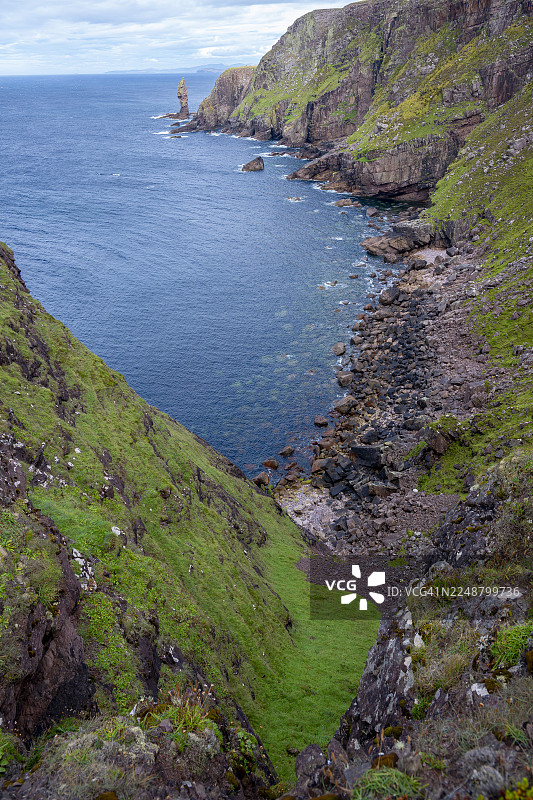 英国苏格兰高地海岸的戏剧性景观，绿色悬崖俯瞰着阴云密布下的深蓝色大海，老斯托尔人图片素材