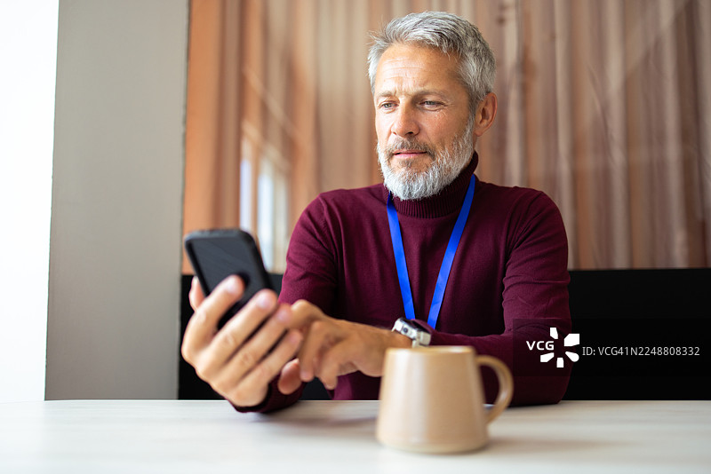 中年商人办公室咖啡休息时间使用手机图片素材