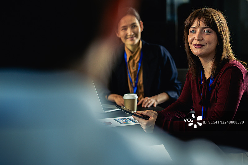 女商人们参加会议，面带微笑并使用平板电脑图片素材