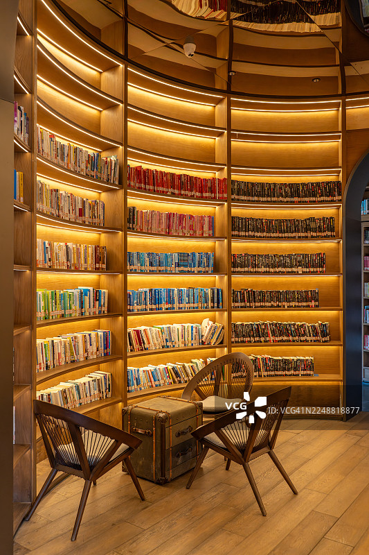 黄色灯光下的图书馆墙壁上摆放着许多书籍图片素材