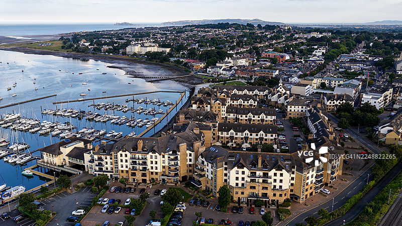 爱尔兰都柏林马拉海德码头和沿海住宅区的日落鸟瞰图，船只停泊在平静水面上的有序排列中，传统海滨城镇布局，现代公寓和风景优美的天然河口，旅行和生活方式概念图片素材