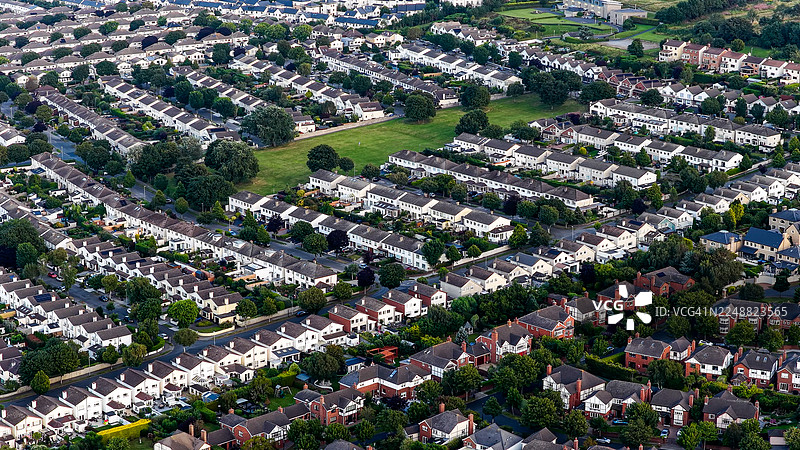 日落时都柏林马拉海德住宅区的空中俯瞰图，背景为码头和海岸景观，传统欧洲城镇建筑，带有斜屋顶和统一的住房，房地产和城市规划概念图片素材