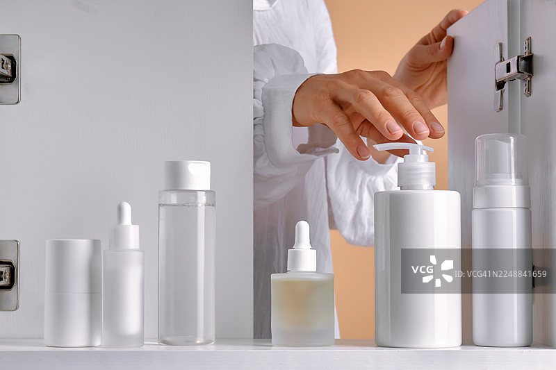 女士在浴室柜中挑选护肤品图片素材