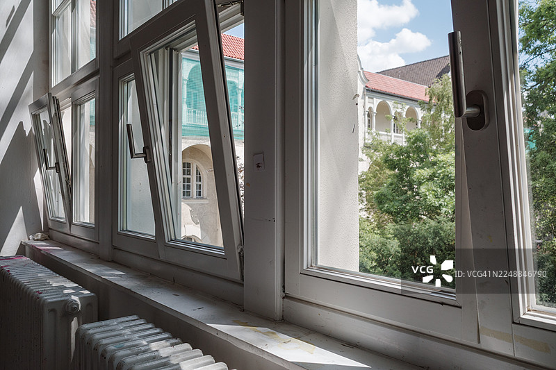 一排现代白色框架的窗户，其中几扇向外倾斜以通风。图片素材
