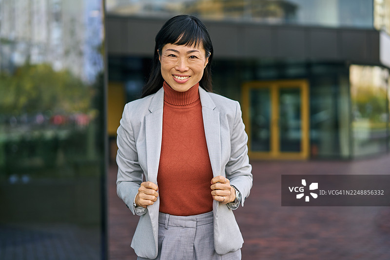 自信地站在城市环境中的微笑亚洲女商人图片素材
