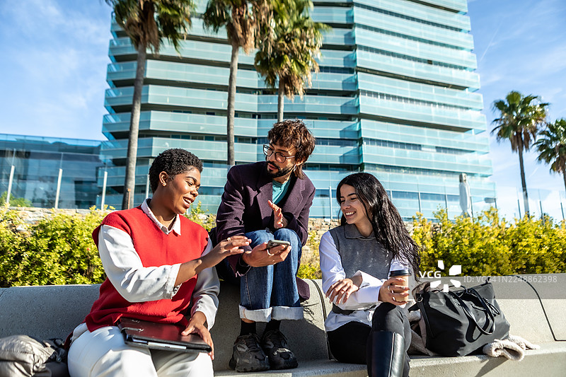不同背景的同事在户外用智能手机规划下一步图片素材