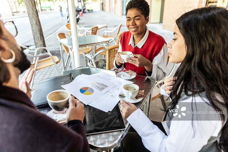 不同肤色的女商人在户外咖啡馆讨论营销报告图片素材