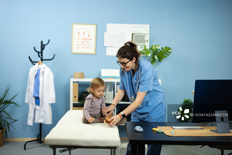 儿科医生在诊所检查时逗弄婴儿图片素材