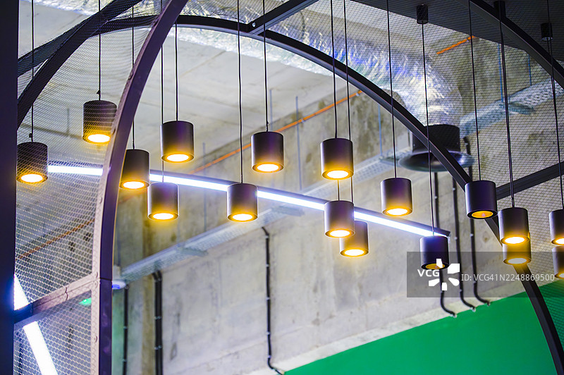 现代工业吊灯照亮了带有显露管道的天花板图片素材