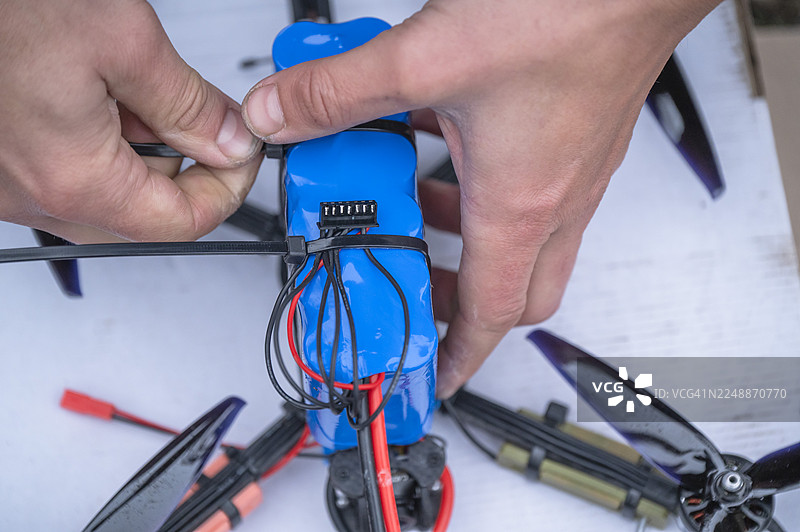 一个人用扎带固定无人机电池的手图片素材