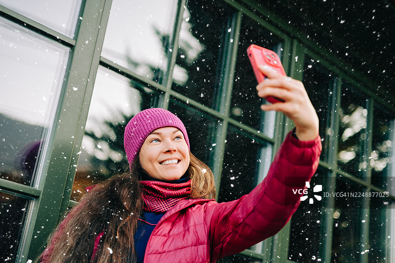 快乐的女人在下雪的冬天户外自拍图片素材