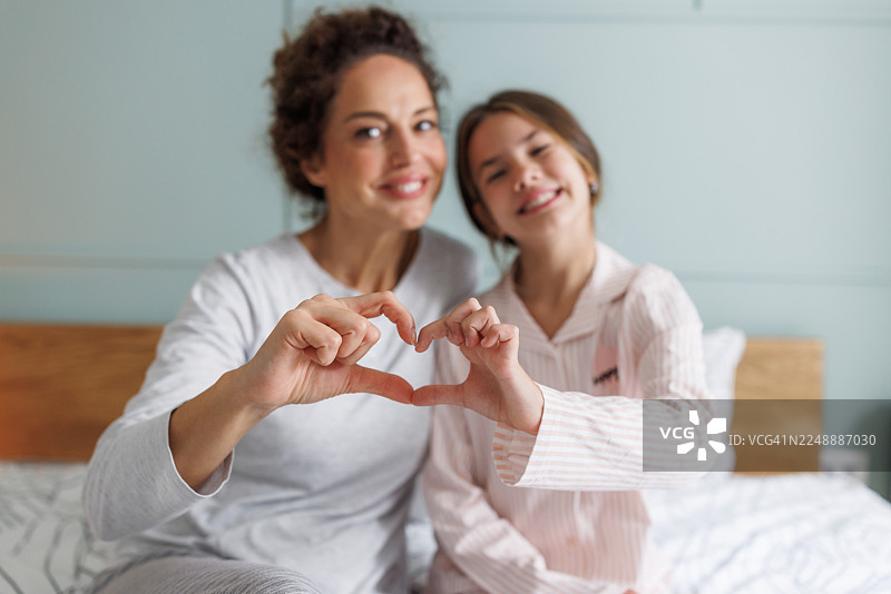 妈妈和女儿在床上用手比心图片素材