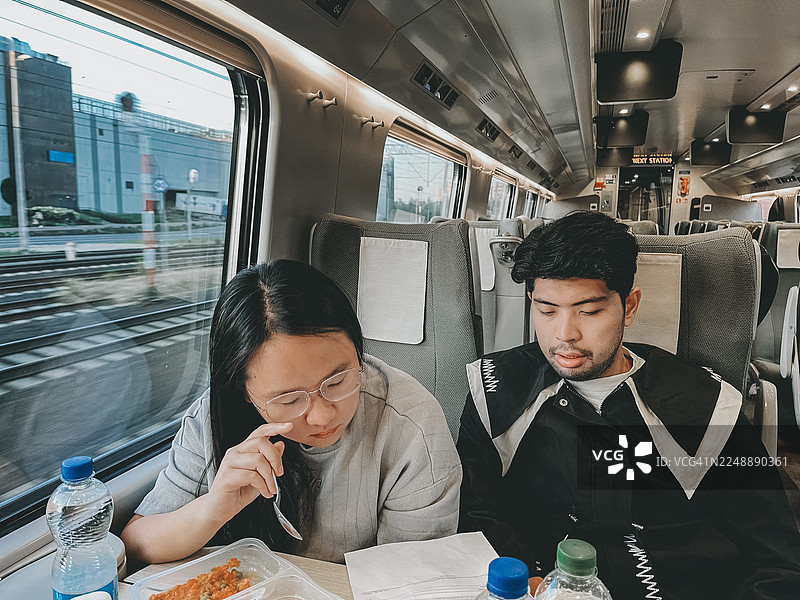 火车通勤者边用餐边使用电子设备。素材照片图片素材