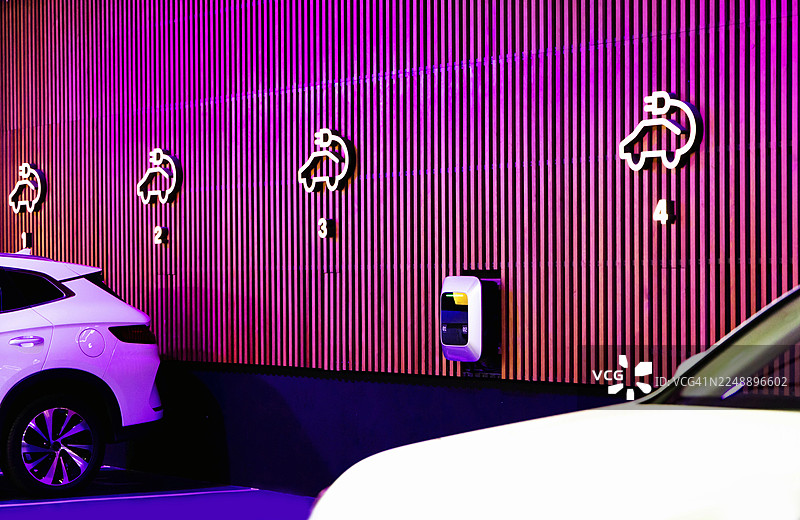 可持续城市交通：电动汽车在现代霓虹灯充电站充电图片素材