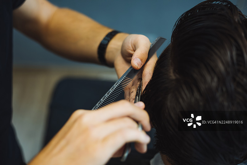 理发师用剪刀近距离修剪侧面头发，捕捉现代沙龙环境中造型的精细细节、手部放置和专业剪发技巧。图片素材