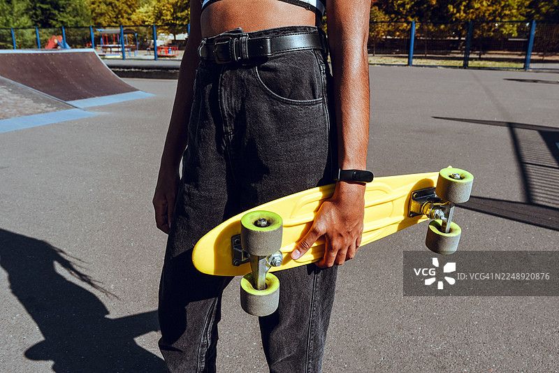 一个黑人女孩拿着滑板。一项活跃的运动。一项适合青少年和儿童的游戏。图片素材