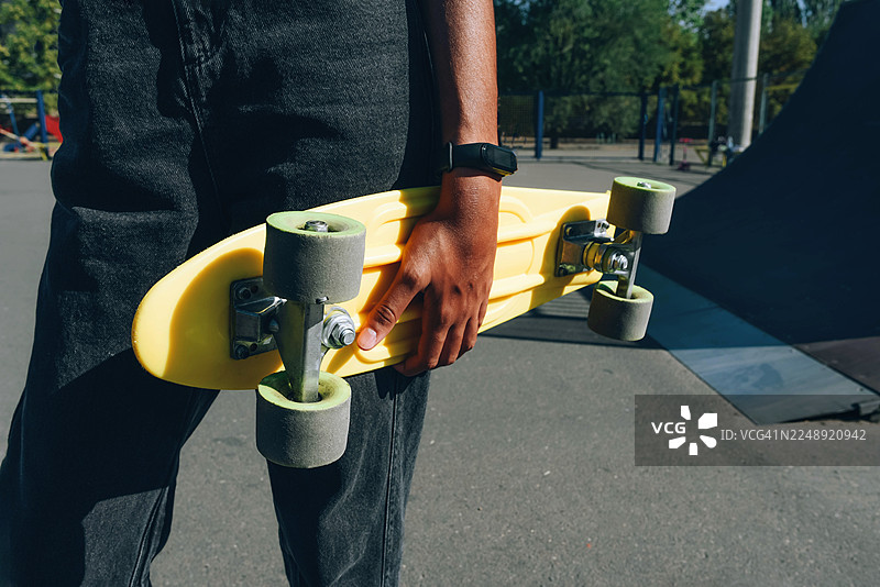 一个黑人女孩拿着滑板。一项活跃的运动。一项适合青少年和儿童的游戏。图片素材