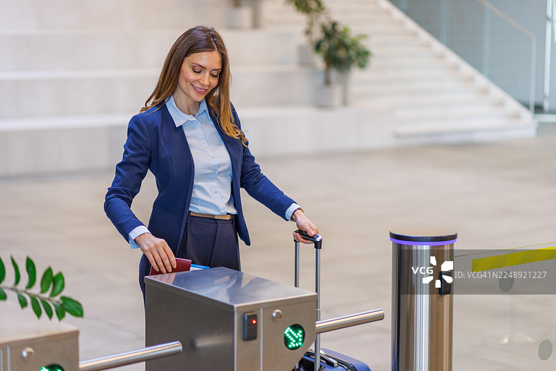 商务女性拖着行李通过机场的旋转门图片素材