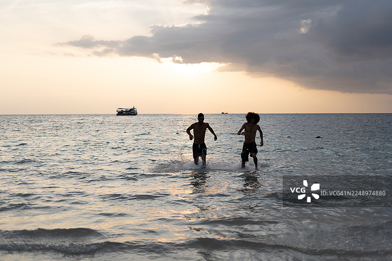 两个朋友在海滩上嬉戏玩水，享受欢乐时光图片素材