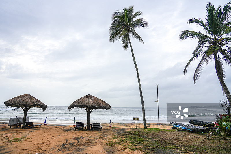 印度喀拉拉邦科瓦兰海滩的斜倚棕榈树下的沙滩小屋遮阳伞图片素材