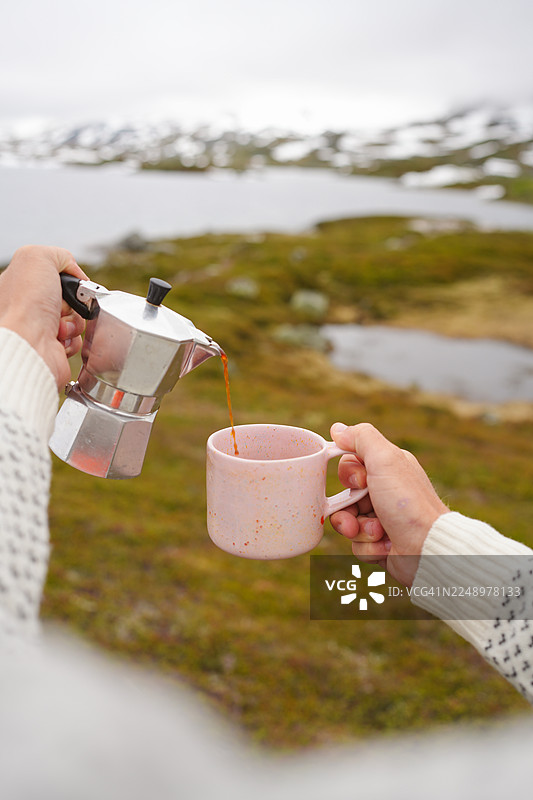 湖边女子将浓缩咖啡倒入杯中的视角图片素材