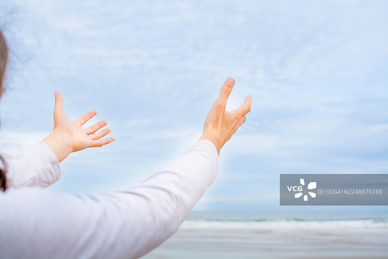 女子在海滩上伸展双臂，拥抱自由图片素材