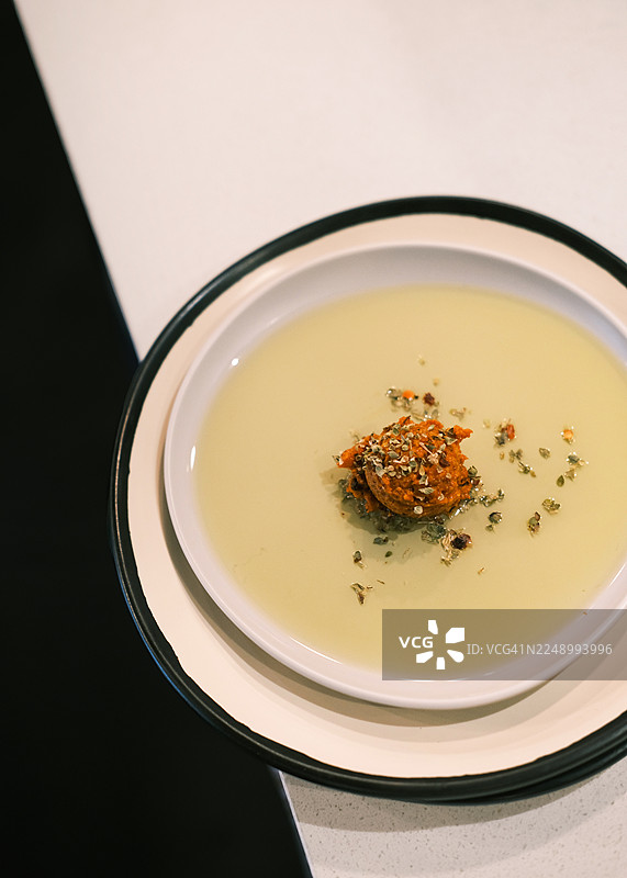 特写俯视视角，在一个白色盘子里，橄榄油中盛放着传统的土耳其开胃菜，上面放着一个带有香料的红辣椒酱球。极简的餐厅摆盘，突出质感和色彩对比，适合菜单设计和美食品牌推广的烹饪理念。图片素材