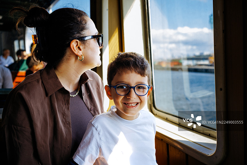 年轻的母亲和儿子在伊斯坦布尔乘坐博斯普鲁斯渡轮游览城市。图片素材