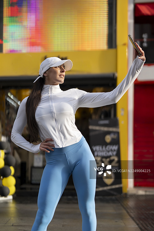 穿着运动服的年轻女子在城市里自拍图片素材